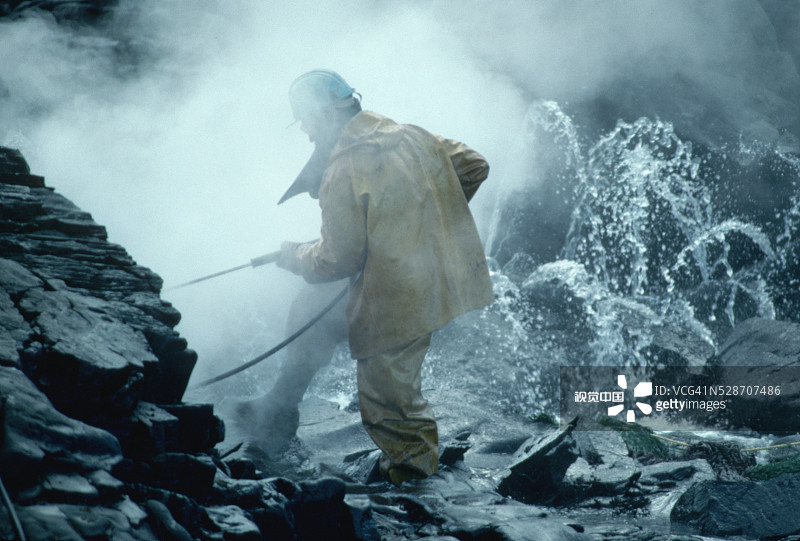 工人喷洒被石油覆盖的岩石图片素材