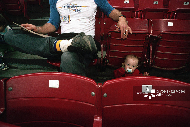 父亲和孩子坐在体育场座位上图片素材