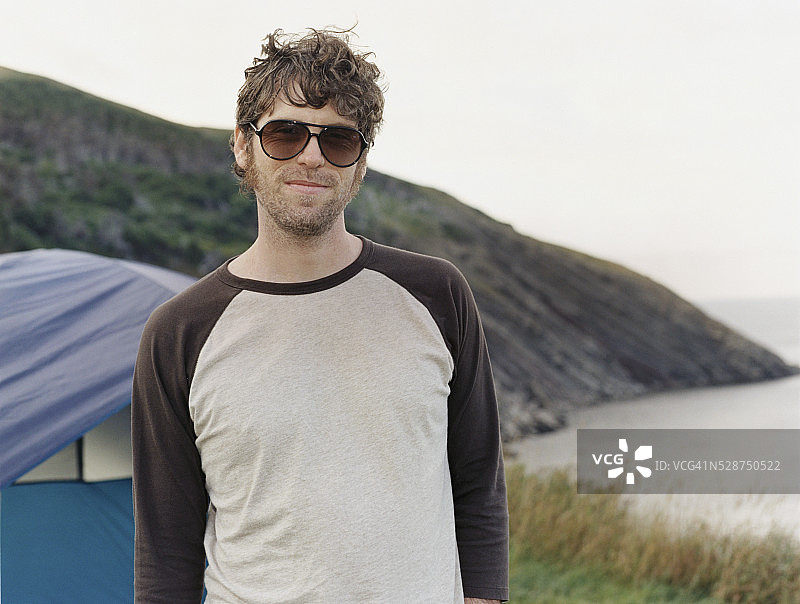 戴太阳镜的男人站在湖边图片素材