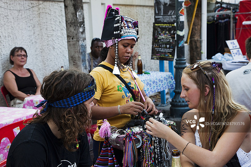 来自泰国北部的苗族妇女在考山路上向游客出售民族珠宝图片素材