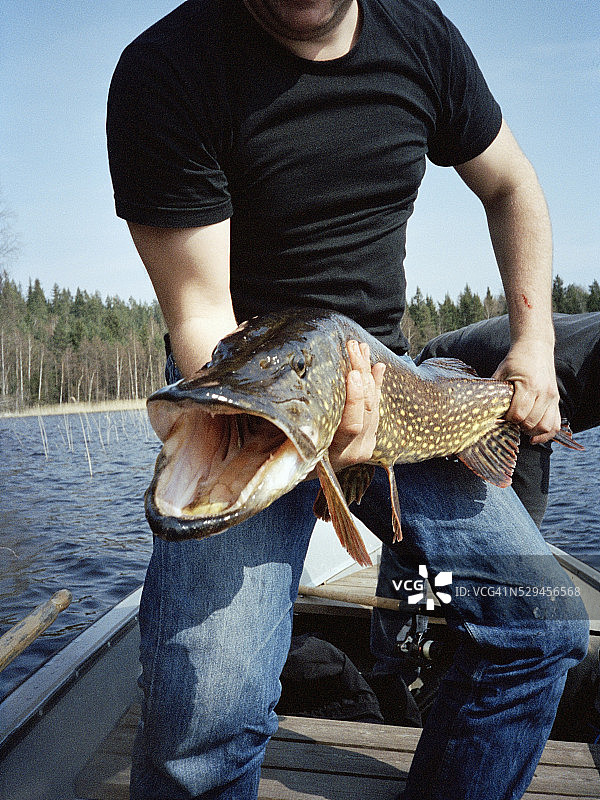 男人拿着一条钓到的大梭鱼图片素材
