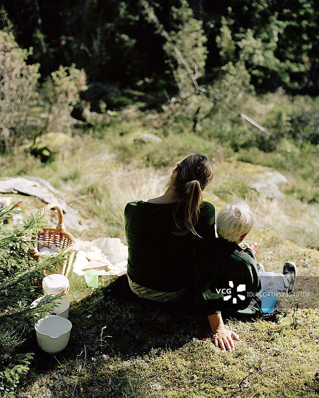 母亲和儿子坐在瑞典的山坡上图片素材