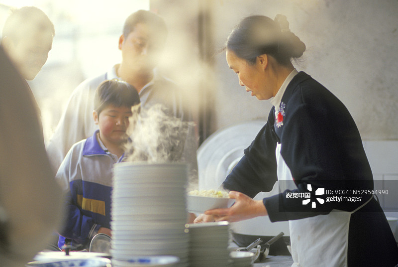女人在食品摊位给男孩提供食物图片素材