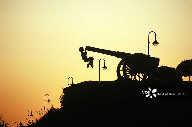 男孩悬挂在炮筒上图片素材