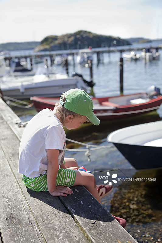 男孩坐在码头上图片素材