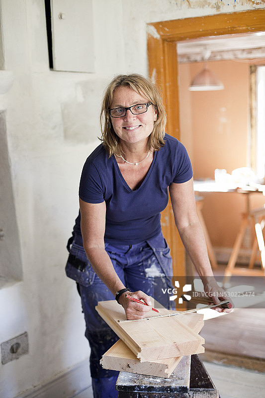 微笑的中年妇女在翻新小屋图片素材
