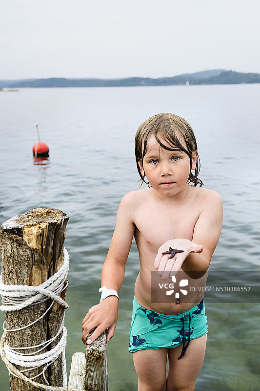 码头上拿着海星的男孩图片素材