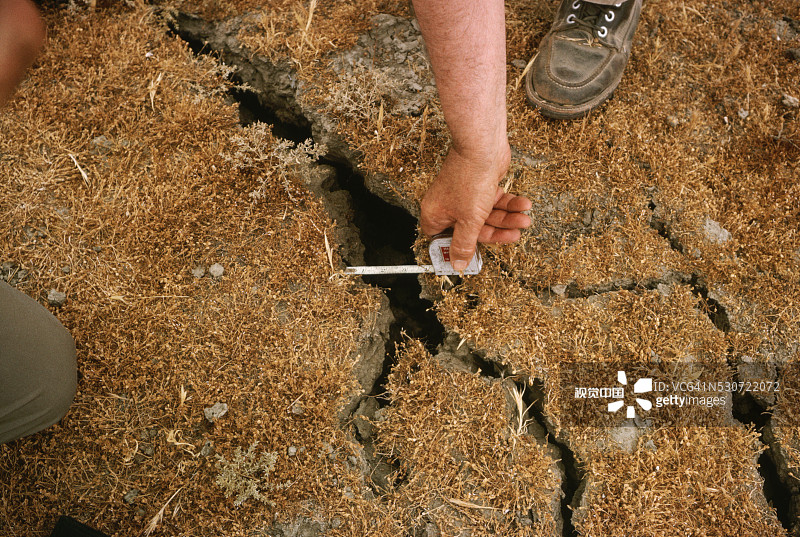 男子测量地面裂缝图片素材
