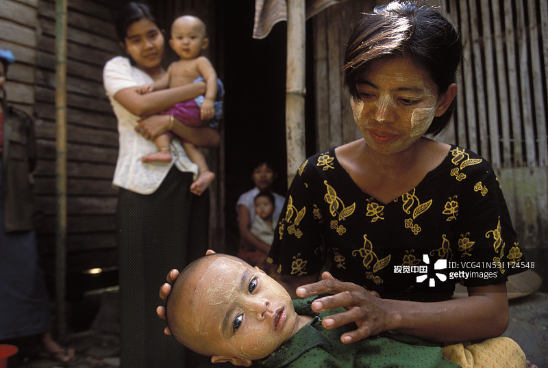 给幼儿脸部涂抹缅甸香木粉的女人图片素材