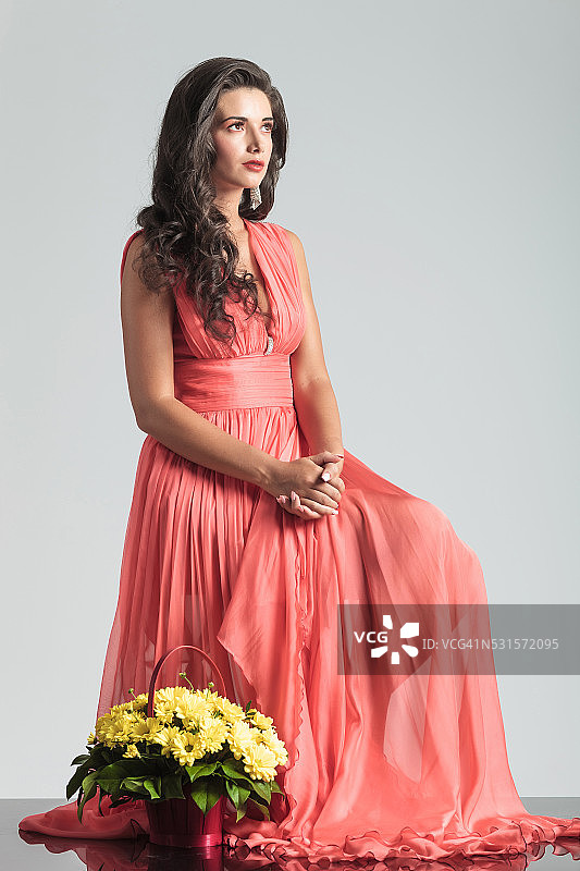 坐在花篮附近的红裙女人图片素材