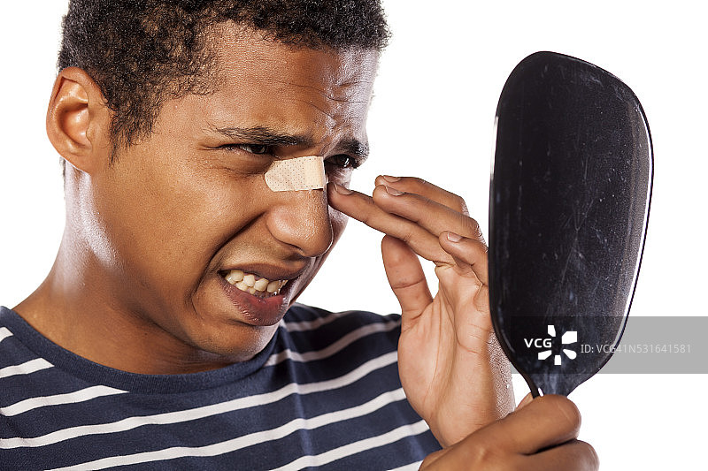 鼻子贴着胶带的悲伤的深色皮肤年轻人图片素材