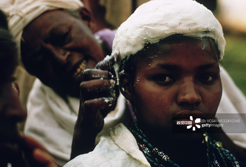 女人给女孩的头部涂抹黄油图片素材