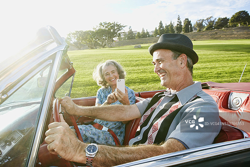 情侣在经典敞篷车里用手机拍照图片素材