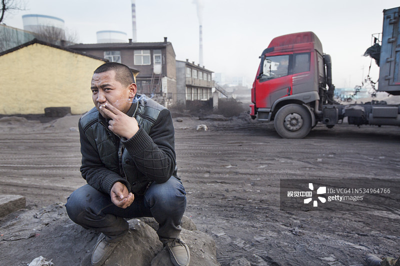 中国大同，在燃煤电站外吸烟的男人图片素材
