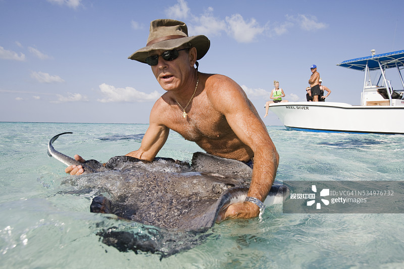男人在旅游船附近拿着黄貂鱼图片素材