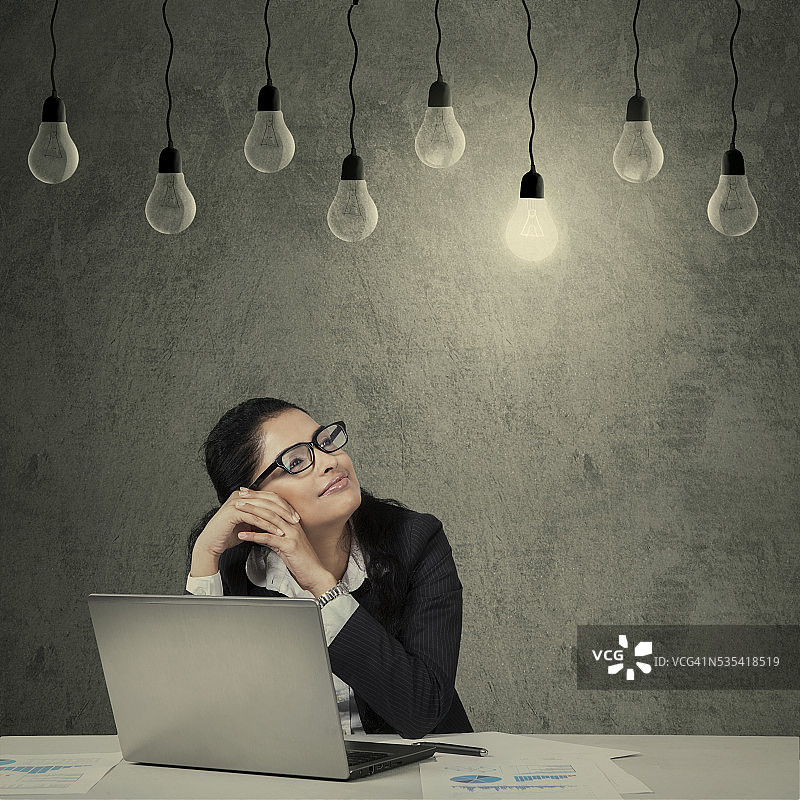 女员工使用笔记本电脑看灯泡图片素材