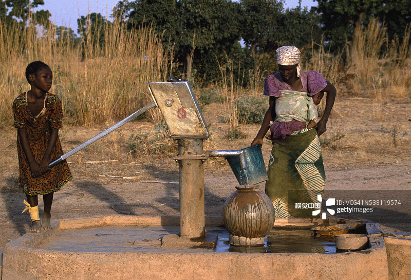 往容器里抽水的年轻女孩图片素材