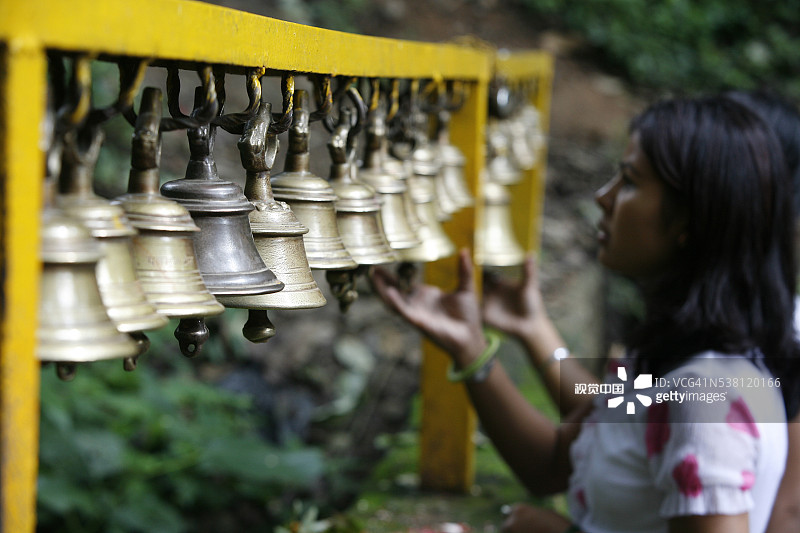 女人在达克辛卡利寺庙敲钟图片素材