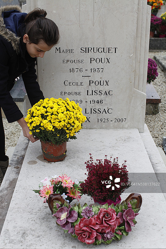 女孩将鲜花放在祖母的坟墓上图片素材