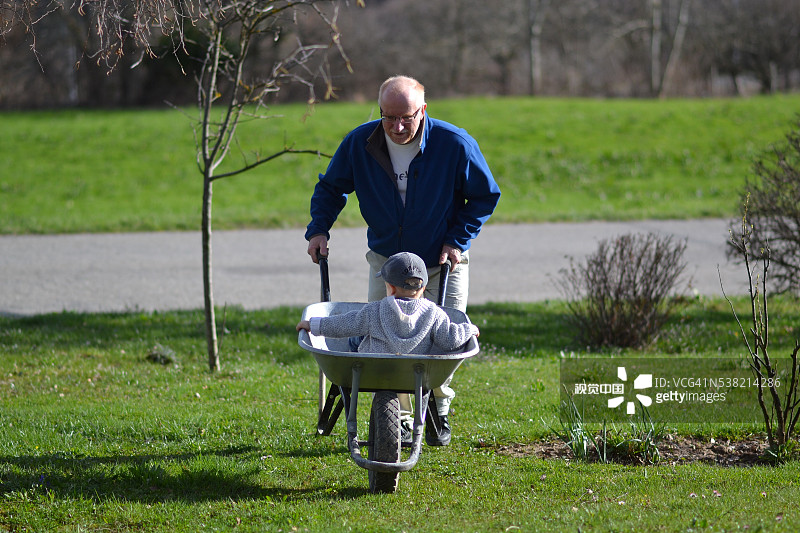 爷爷用手推车推着孙子图片素材