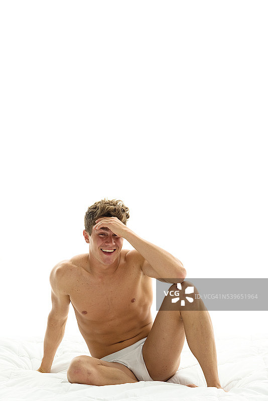 未穿衬衫的健壮男人坐在床上图片素材
