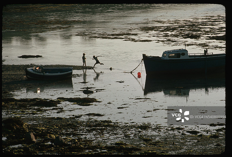 退潮时在港口玩耍的男孩们图片素材