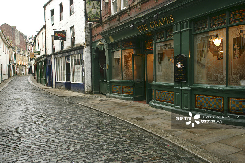雨天鹅卵石街道上的酒吧和商店图片素材