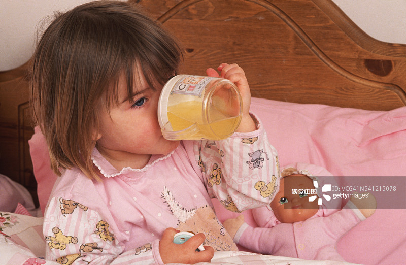 在床上喝果汁的幼儿图片素材