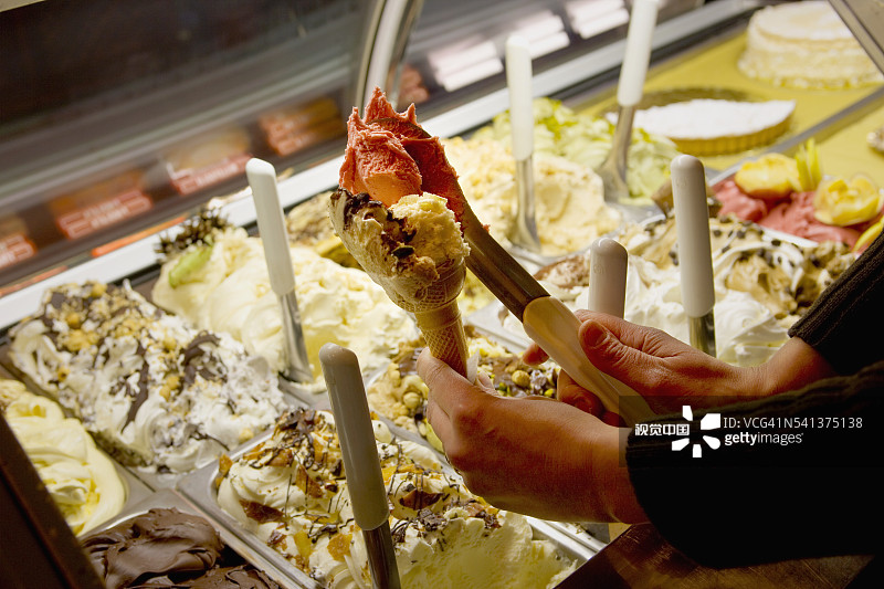 女人在时尚商店将冰淇淋舀到甜筒上图片素材