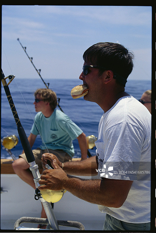 男人在船上吃饭和钓鱼图片素材