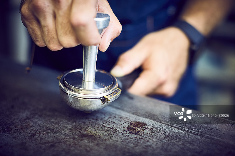服务员的手压在研磨咖啡上图片素材
