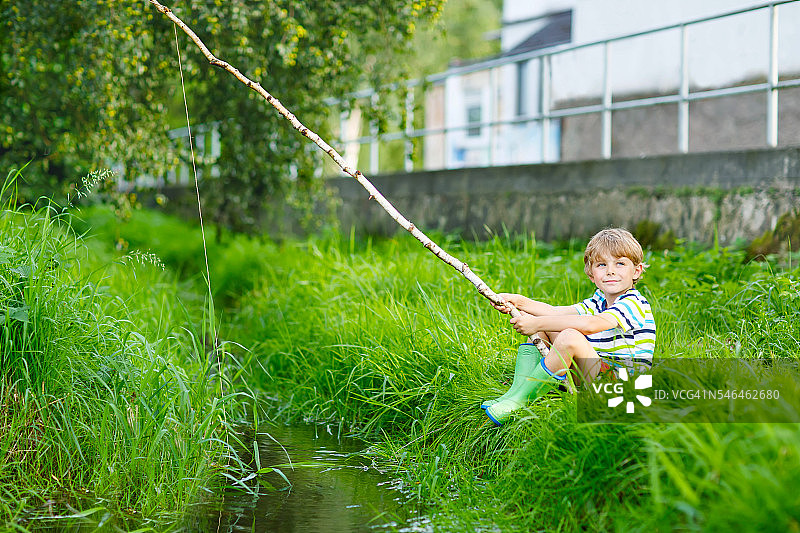 小男孩河边用自制鱼竿钓鱼图片素材