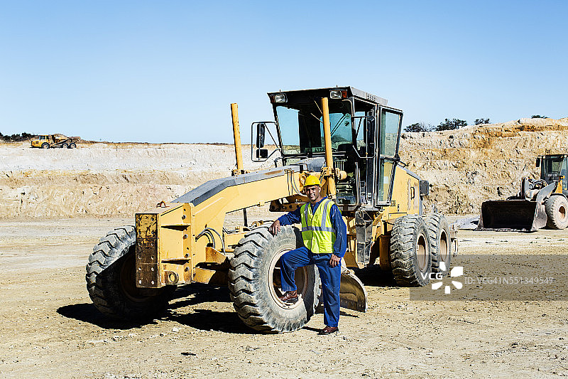 建筑工人在采石场靠在推土机上图片素材