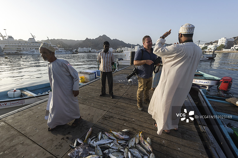 一位摄影师在鱼市场与他的助手讨论拍摄地点。图片素材