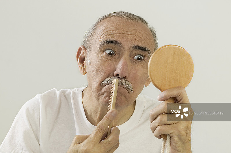 年长的男人拿着镜子梳理胡须图片素材