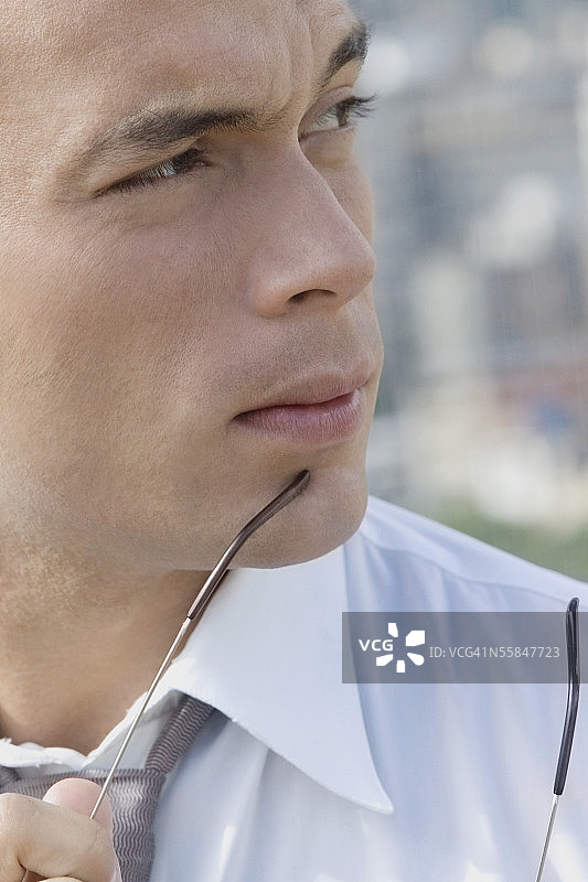 年轻男人手持眼镜的肖像图片素材