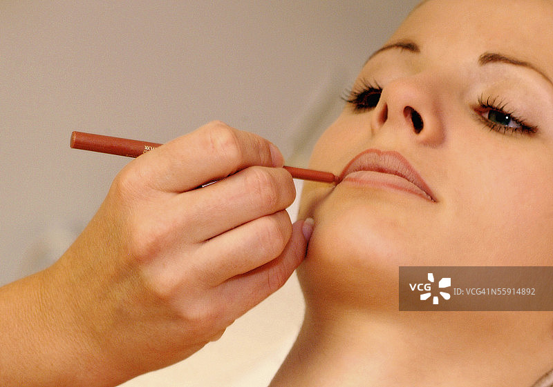 美容师为中年妇女涂抹唇线图片素材