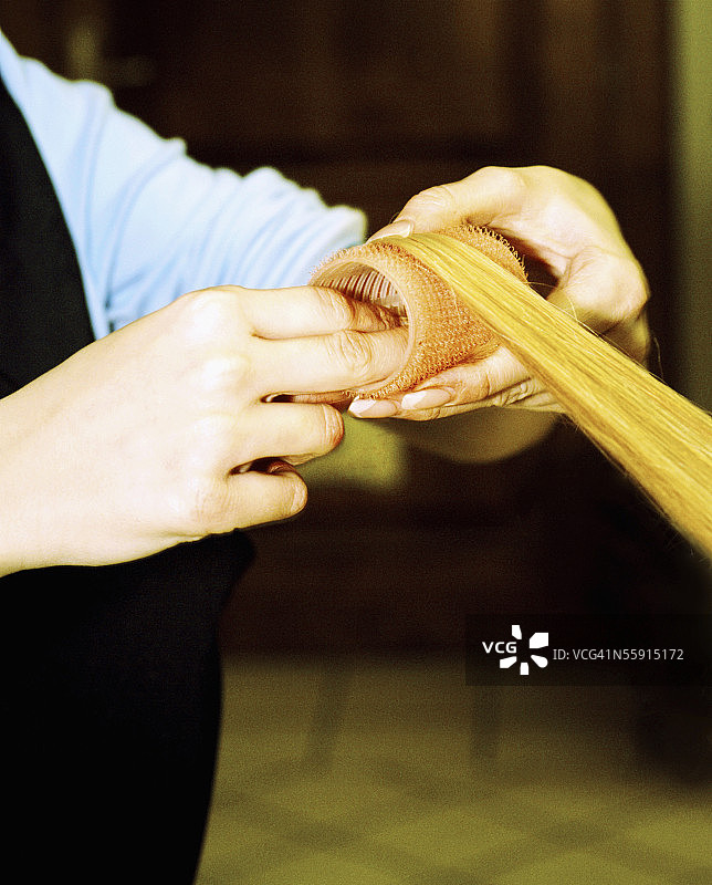 美发师的手在调整女人头发上的卷发器特写图片素材