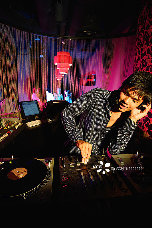 年轻男子戴着耳机在俱乐部打碟图片素材