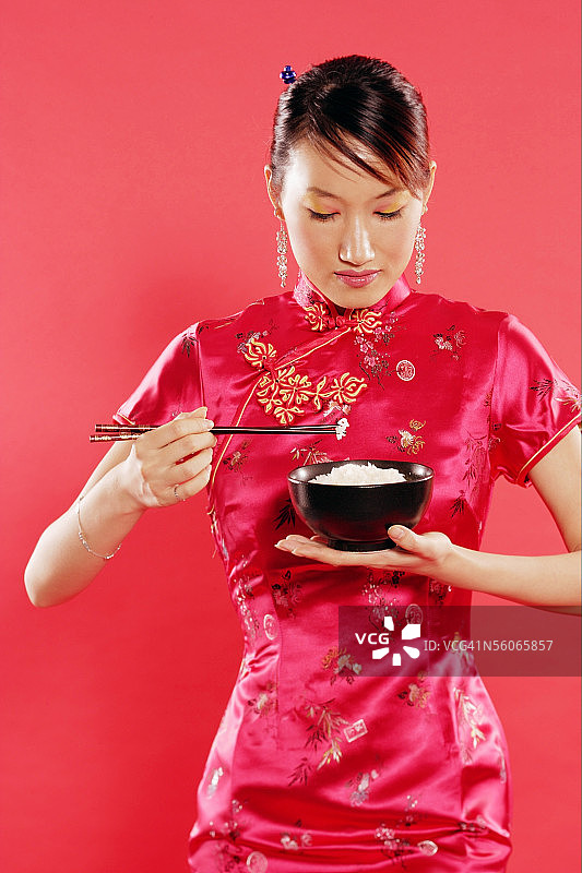 穿旗袍，手捧米饭和筷子的女人图片素材