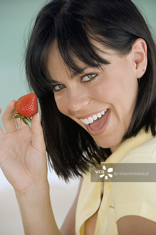 年轻女人在沙滩上拿着草莓的画像图片素材