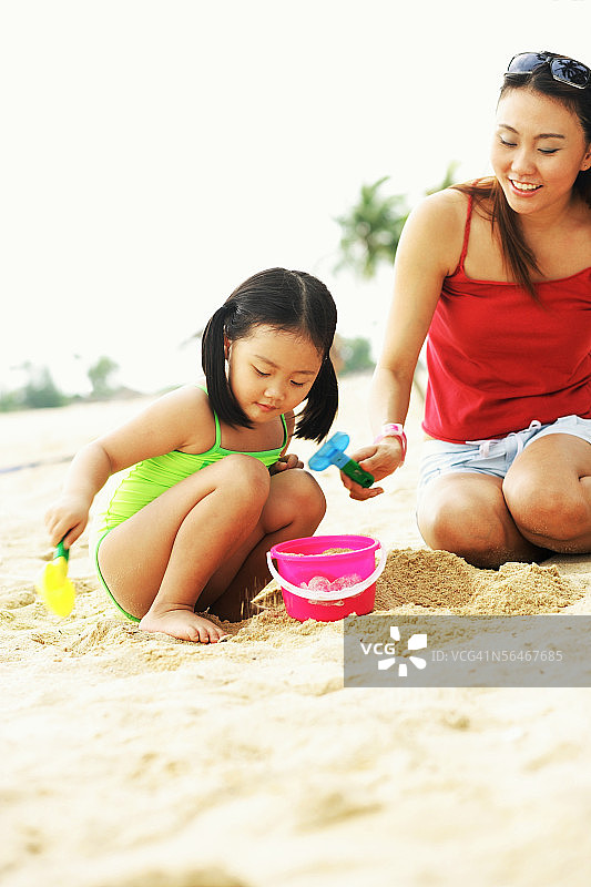 母亲和女儿在沙滩上玩沙子图片素材
