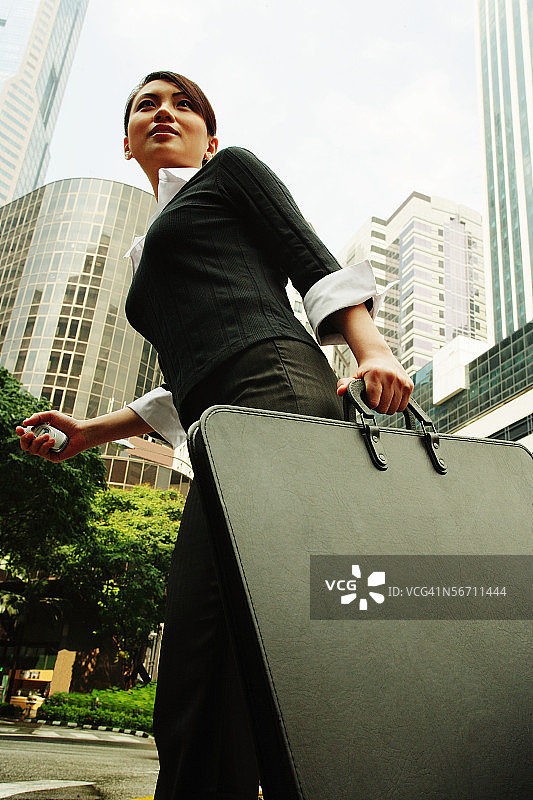 手提公文包在建筑物背景中行走的商务女性图片素材