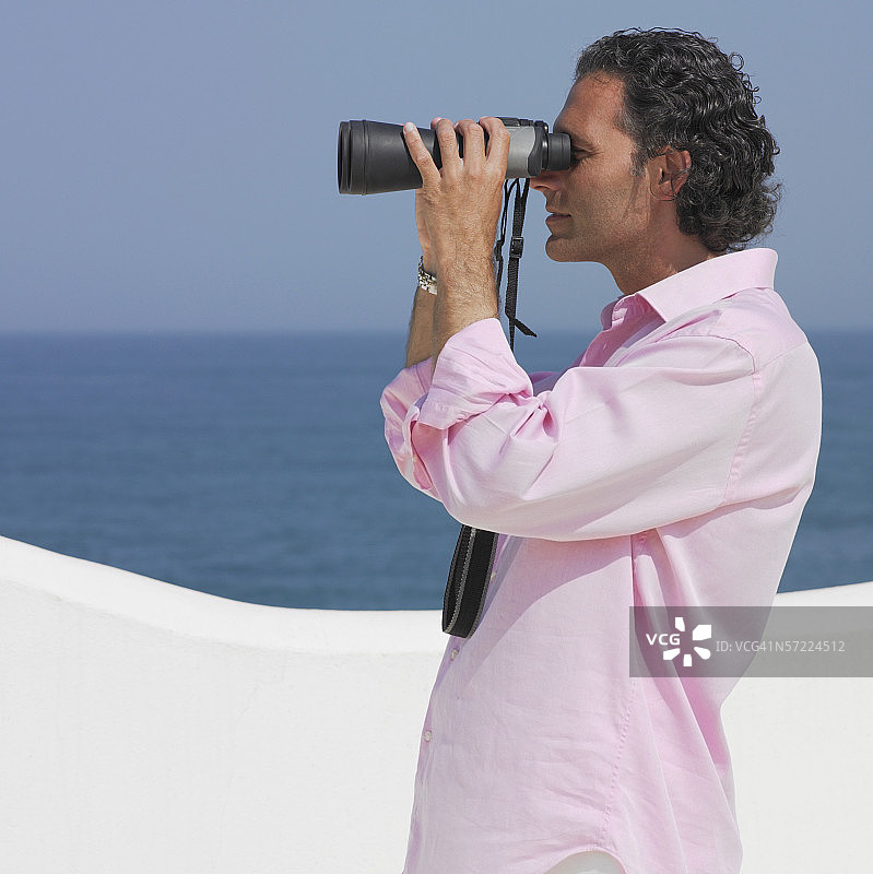 中年男人用双筒望远镜看海图片素材