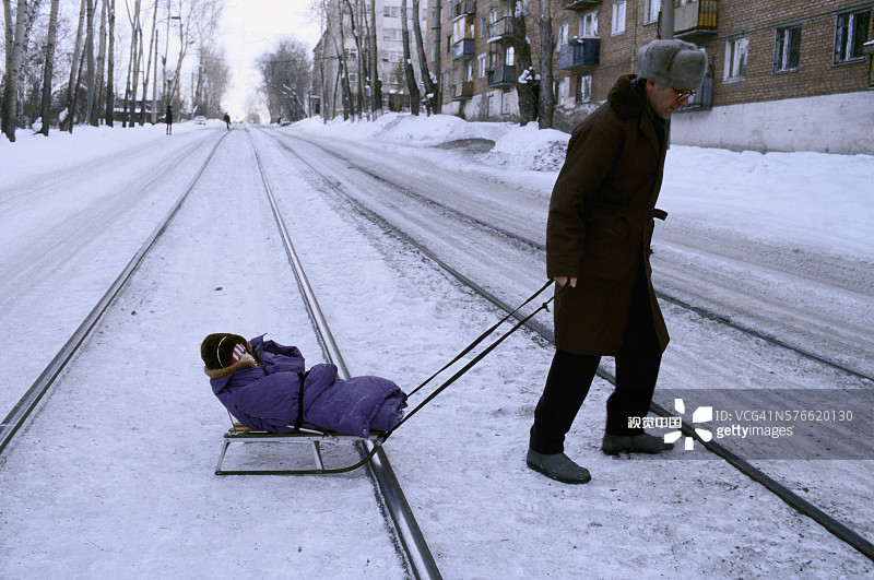 父亲拉着雪橇上的孩子图片素材