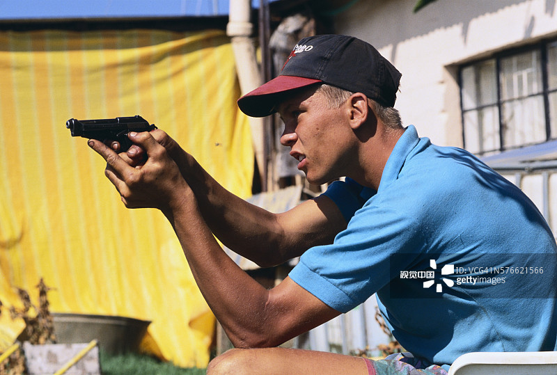 年轻男人在南非后院使用手枪图片素材
