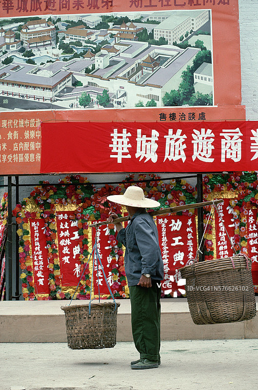 男子用扁担平衡地挑着两个篮子图片素材