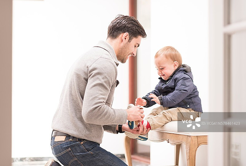 父亲帮助小儿子穿鞋图片素材