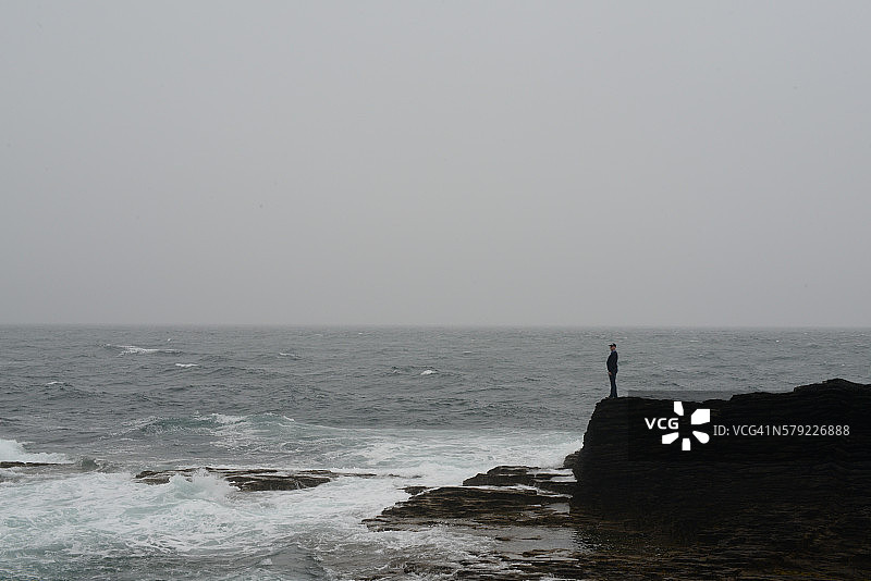 海边岩石上的单身男人图片素材
