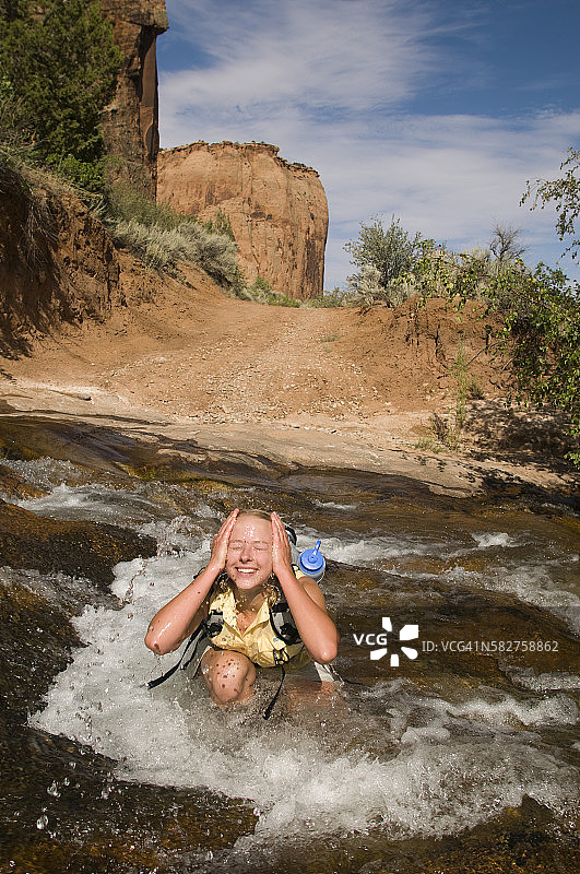 在犹他州沙漠小溪中泼水的女人图片素材